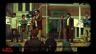 Still camera footage of a man speaking to a public crowd through a megaphone. Some people are standing behind him on stage.