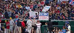 Baseball fans near the dugout hold signs saying "Capitol police MVP" and "Scalise Strong".