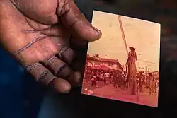 The hand of the enigmatic Dexter Stewart holds a photograph from his early days as a Moko Jumbie.