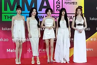 Photograph of five women wearing white dresses