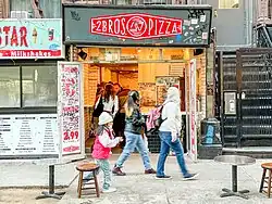 A small storefront along a sidewalk with a sign reading, "2 BROS PIZZA"