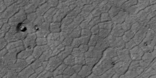 Close view of polygons, as seen by HiRISE under HiWish program This image also shows anenlarged view of a boulder sitting in a pit. Pits may have formed from the interaction of winds around the boulders. Winds may go faster near the boulder; hence, causing more erosion.