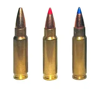 Photo of three 5.7×28mm cartridges as used in the Five-seven pistol. The left cartridge has a plain hollow tip, the center cartridge has a red plastic V-max tip, and the right cartridge has a blue plastic V-max tip.
