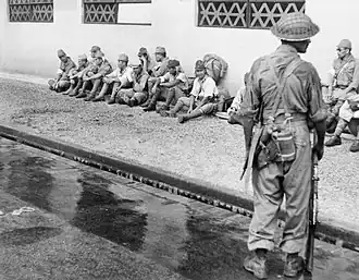 A soldier from the 5th Indian Division stands guard over Japanese prisoners