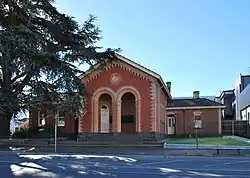 A small symmetrical red brick building with a recessed entry and a gabled roof.