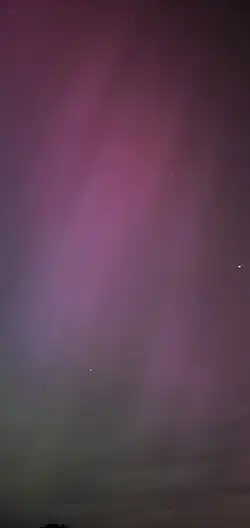 A picture of the sky with red at the top, which fades to green at the bottom, with some streaking grey vertical lines.