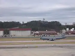 A KC-135R Stratotanker departing with the Alabama Air National Guard hangars and buildings behind.