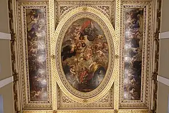 On a painted ceiling, angels surround a king dressed in red.