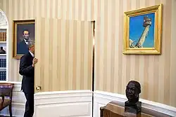 Barack Obama framed by a bust of Martin Luther King Jr. and a painting of Abraham Lincoln