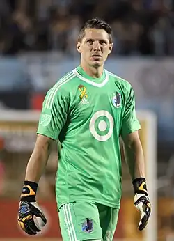 A soccer goalkeeper in a green jersey is standing.