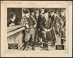 Lobby card showing a comedic scene from the film with characters in period costume standing at a bar