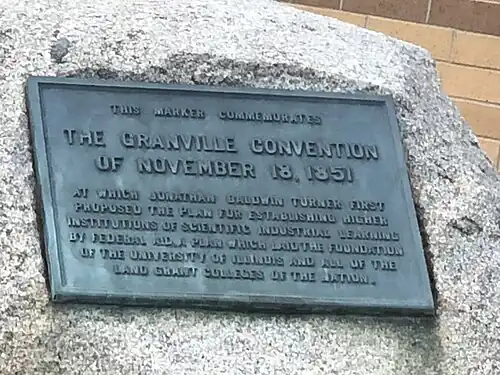 A boulder bearing a oxidized bronze inscription dedicated to Turner's "plan for establishing higher institutions of scientific industrial learning by federal aid plan which laid the foundation of the university of Illinois and all of the land grant colleges of the nation."