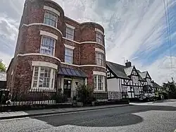 Bow windows of Georgian house with a 1600s timber framed house beside in Wem