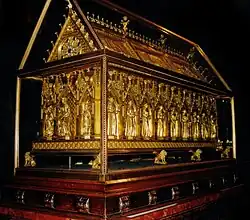 The reliquary is a large rectangular box with a gabled lid, giving it the appearance of a small temple. It is sculptured with architectonic details in the Gothic style and rests on feet in the shape of small lions. It has nine sculptured niches on each side and three at the ends in which stand small statues of the martyrs and patron saints. While there are a number of semi precious stones in the apex of each niche, the richness of the object comes from the delicate and elaborate quality of the metalwork demonstrating many techniques such as filigree, engraving and embossing.