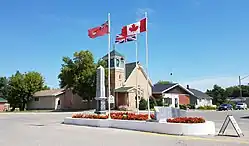 A Canadian Red Ensign, Royal Union Flag, and the flag of Canada flown next to a cenotaph in Cartwright, Manitoba