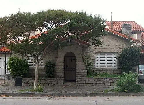 Yet another example featuring a vault-shaped, stone cladded porch on front with false gable hidden by a tree top and false chimney