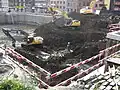 Archaeologists clear the counterscarp amidst the construction machinery.[13]