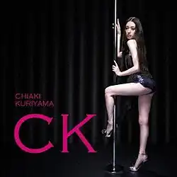 A long haired woman wearing a short black dress and high heels holds a dance pole, and wraps her left leg around the pole. The background is a dark stage, and there is pink font saying "Chiaki Kuriyama" in small letters, and "CK" in large letters.