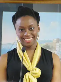 African woman in black dress and yellow scarf smiling