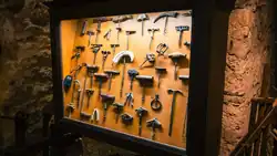This image showcases a framed display of corkscrews inside the Musée du Vin (Wine Museum) in Paris, France. The collection is arranged behind a glass panel and features a variety of corkscrews, highlighting different designs and mechanisms used throughout history for opening wine bottles. The exhibit reflects the evolution of wine-related tools, from traditional T-shaped corkscrews to more intricate lever-style and mechanical models.