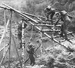 Man climbing over assault course wooden obstacle