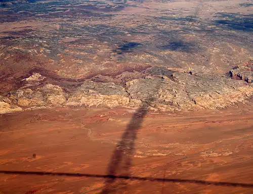 Shadows of contrails over San Rafael Reef — San Rafael Swell, Reef (perimeter), and San Rafael Desert at south & southeast. The Reef is most of the southeast, and east perimeter of the 45-mile-wide (72 km) (west-to-east) San Rafael Swell, which trends southwest-by-northeast.