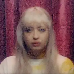 A blurry photo of the artist in front of a red curtain