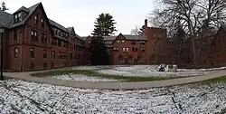 A panorama of the courtyard and winged sides of a three- and four-story brick dormitory
