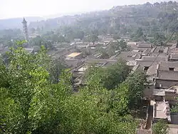 Look from above at a traditional village, with a pagoda in the background