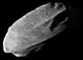 A small, irregularly shaped body elongated from the bottom left to top right. It is illuminated from the bottom left.