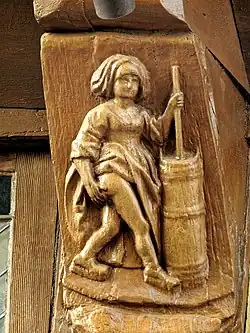 Witch holding a churn full of cream in her left hand.
