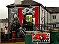 Gable-end mural, vandalised with green paint,[note 22] showing Raymond McCartney and a female hunger striker from 1980
