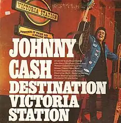 Portrait of a smiling man holding a guitar and standing on the stairs of a railroad car.