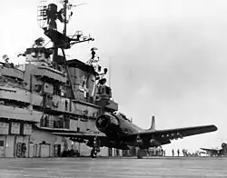 A propeller-driven aircraft prepared to take off aboard an aircraft carrier deck