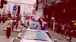 Lipa in a limousine sticking her head out of the sunroof as it drives around Soho, London.