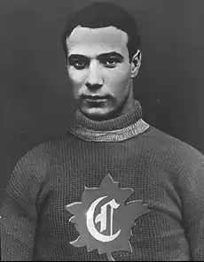Half-length view of an ice hockey player in his late twenties. He has short black hair and a serious look. He is wearing a sweater with the letter C surrounded by a maple leaf on the chest.