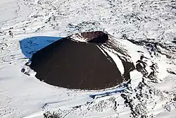 A partially snow-covered, cone-shaped volcano with a bowl-shaped crater on its top.