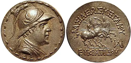 Silver Tetradrachm of king Eucratides I wearing a helmet decorated with bull's horn and ear. Reverse shows the Dioscuri on horseback. Greek legend: ΒΑΣΙΛΕΩΣ ΜΕΓΑΛΟΥ ΕΥΚΡΑΤΙΔΟΥ, Basileōs Megalou Eukratidou, "Of Great King Eucratides".