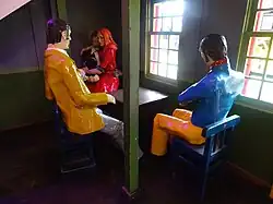 Three painted wooden figures sitting at a table