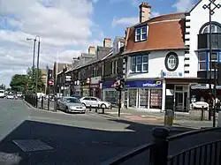 A terrace of stone fronted buildings, with a curved corner building fronted in white, from the mid-late 19th century