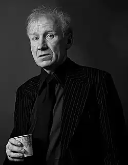 Eddie Linden wearing a suit and holding a cup