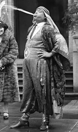 Artist painting of dark-skinned man in turban in side profile; his head is thrown back and four streams of liquid are fountaining from his mouth