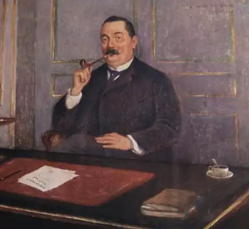 Stout middle aged white man with dark hair and moustache, sitting at a desk, smoking a pipe