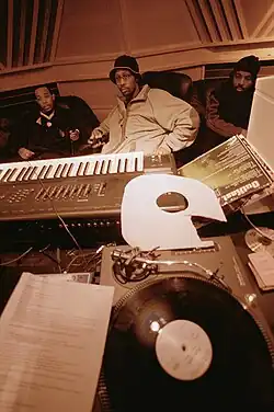 Image 6Hip hop producer and rapper RZA in a music studio with two collaborators. Pictured in the foreground is a synthesizer keyboard and a number of vinyl records; both of these items are key tools that producers and DJs use to create hip hop beats. (from Hip-hop production)