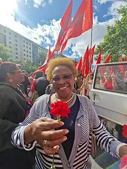Inocência Mata holding a carnation in front of a crowd