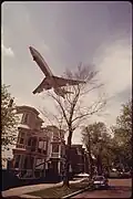 Jet zooms over southwestern side of Neptune Road. (May 1973)