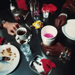 A table with two different men's arms and glasses of water, cups, plates and other objects on it.