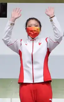 Jiang Ranxin at the 2020 Summer Olympics, wearing a face mask and team jacket, waving her arms in celebration.