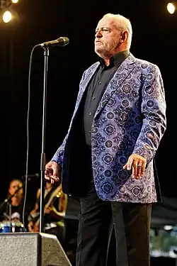 English musician Joe Cocker, standing before a microphone.