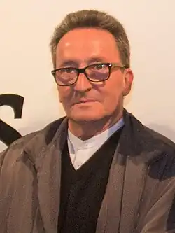 Close up of a man standing wearing glasses.